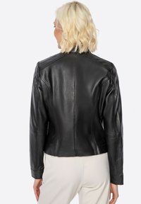 Black leather jacket with a fitted design, featuring structured shoulders, smooth texture, and a cropped back hem.