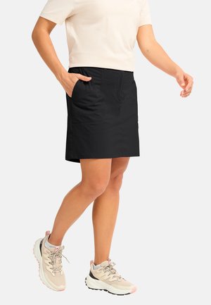 Black skort with two front pockets, featuring a smooth texture and a knee-length cut. Paired with light-colored athletic shoes.