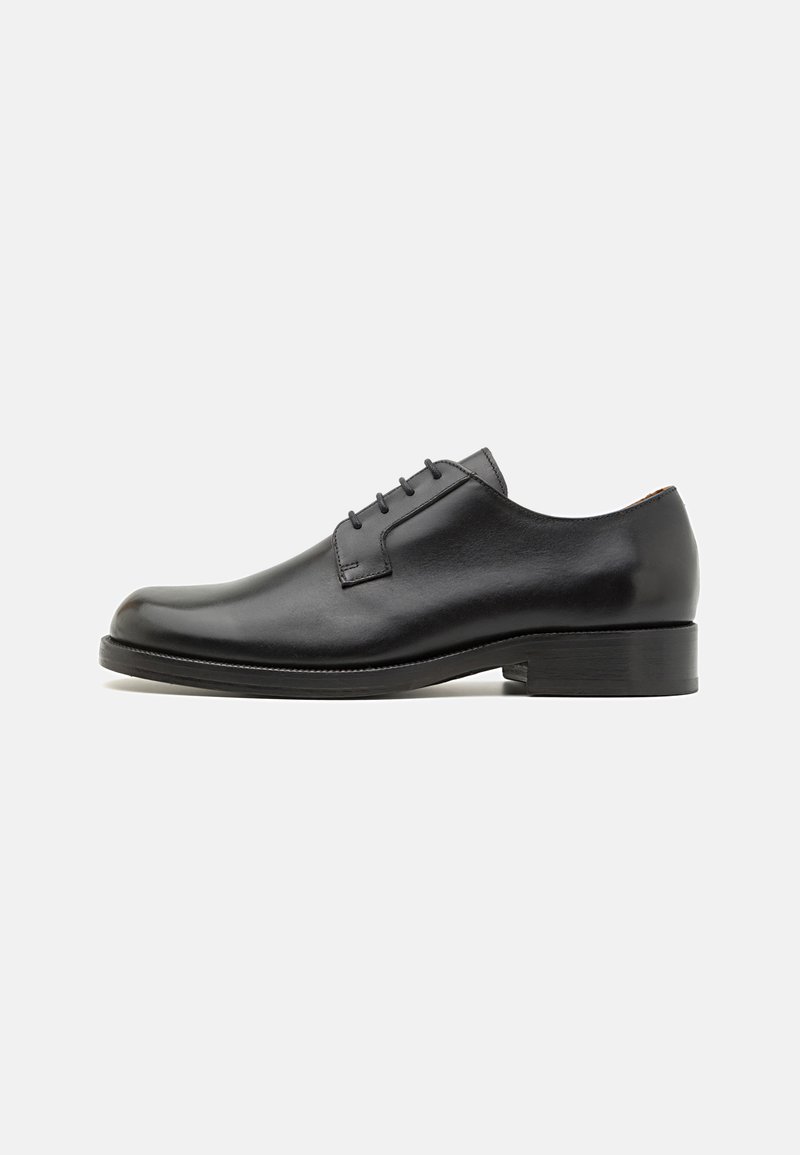 Scarpa oxford in pelle nera con punta rotonda, cinque occhielli per i lacci e tacco basso impilato. Texture liscia e design minimalista.