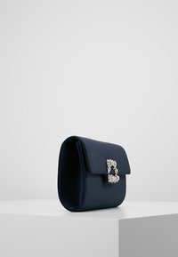 Námořnická saténová kabelka s klopovým uzávěrem a zdobenou sponou ve tvaru "B". Obdélníkový tvar, hladký povrch, kompaktní design.