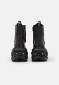 Svarta läderankelstövlar med kraftig sula, bakdragkedjor och dekorativ hårdvara. Har en slät yta och dragöglor.