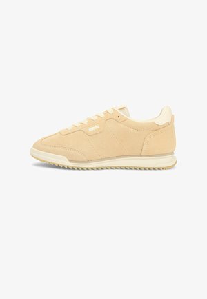 Beige suède lage sneaker met witte veters, crèmewitte zool en een geribbelde buitenzool, gezien vanaf de buitenkant op een witte achtergrond.