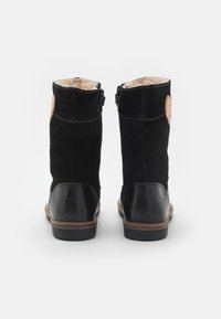Botines de ante negro con detalles en cuero y un forro texturizado y cálido. Incluyen una lengüeta para ponérselos fácilmente y detalles de costura en contraste.