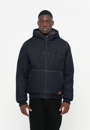 Dark denim jacket with a hood, zip closure, and front pocket. Features ribbed cuffs and hem, with a textured fabric and brown label detail.