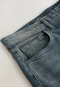 Jeans aus Denim in hellblau mit einem verblassten Finish. Verfügt über eine Gesäßtasche, Gürtelschlaufen und kontrastierende Nähte im klassischen Fünf-Taschen-Design.