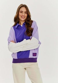 Fioletowy i lawendowy pulower w blokach kolorystycznych z kołnierzykiem, z białymi rękawami i prążkowanym dołem. Zawiera małą metkę.