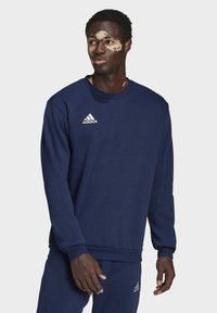 Mørkeblå sweatshirt lavet af blødt stof, med rund halsudskæring og lange ærmer. Hvid Adidas-logo på venstre bryst.