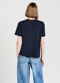 T-shirt a maniche corte blu navy realizzato in tessuto morbido, con una trama sottile, scollatura rotonda e vestibilità rilassata, abbinato a jeans in denim chiaro.