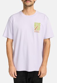 Lavendel bomulds t-shirt med korte ærmer har et palmetræ grafik i grøn og brun på venstre brystområde. Klassisk afslappet pasform.