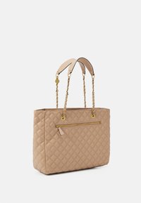 Sac fourre-tout beige matelassé avec poignées en chaîne et cuir, doté d'une poche zippée à l'avant et de ferrures dorées. Finition texturée sur l'ensemble.