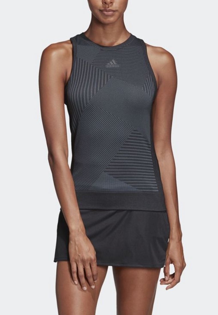 Top deportivo negro de corte atlético con patrones geométricos y textura acanalada, que presenta un escote alto y un logo. Combina con una falda negra.