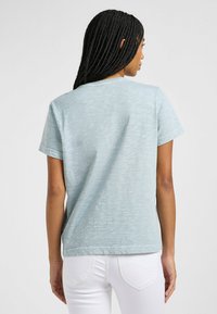 T-shirt azzurro chiaro a maniche corte realizzato in tessuto testurizzato, dotato di scollatura a girocollo e di un taglio dritto all'orlo.