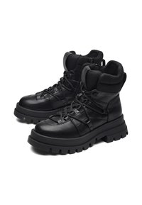 Mustat, korkeavyötäröiset nahkakengät, joissa on teksturoitu verkko-kaulus. Varustettu paksuilla kumipohjilla, nauhakiinnityksellä ja minimalistisella muotoilulla.