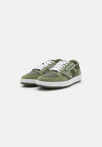 Sneakers verzi din suede și plasă, cu șireturi albe, talpă din cauciuc și un logo proeminent pe lateral. Prezintă detalii perforate și accente contrastante.
