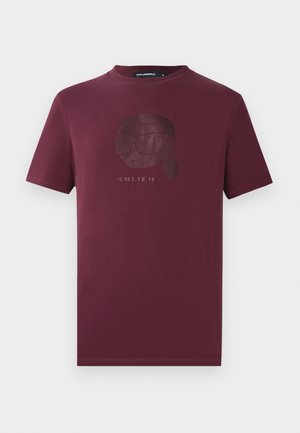 Tricou scurt cu mânecă, de culoare vișinie, cu un grafic subtil lucios al unei persoane purtând ochelari de soare și un text dedesubt, situat în centrul frontal.