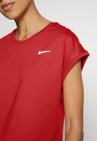Punainen urheilu t-paita lyhyillä hihoilla, pyöreällä kaula-aukolla, valmistettu teksturoidusta kankaasta, jossa on valkoinen Nike-logo rinnassa.