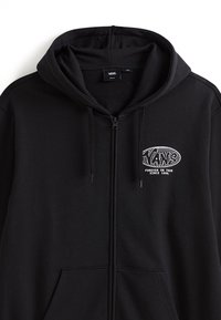 Černá mikina na zip vyrobená z měkké tkaniny, s klokaní kapsou, kapucí se šňůrkami a bílým logem Vans na levé hrudi.
