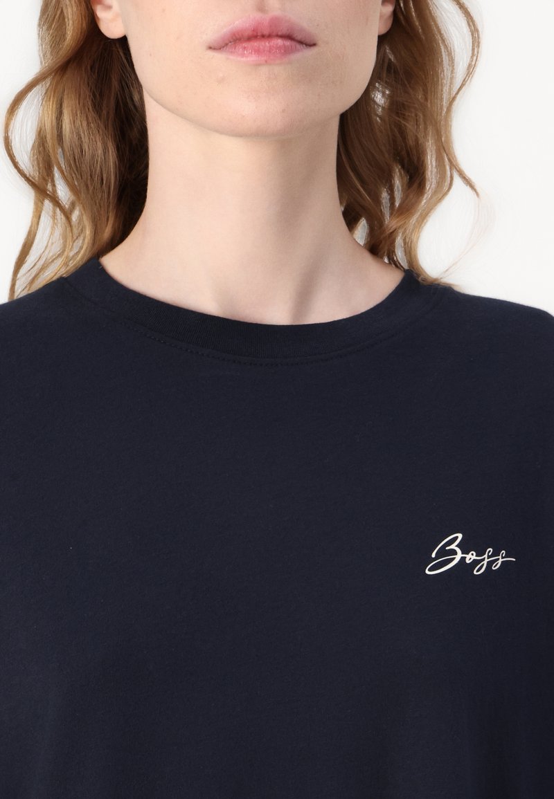 T-shirt en coton bleu marine avec un col rond, ornée du logo "Boss" brodé en blanc sur le côté gauche. Texture douce, manches courtes.