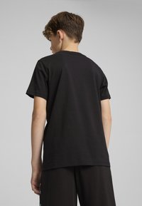 Zwarte katoenen t-shirt met korte mouwen, eenvoudige ontwerpen, ronde hals en een relaxte pasvorm, gezien vanaf de achterkant.