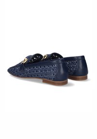 Zapatos planos de color azul marino con parte delantera de tejido trenzado, parte trasera de cuero liso y detalles en metal dorado. Tacón de madera bajo. Diseño abierto.