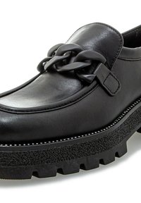Mocasín de cuero negro con una suela gruesa y texturizada, que presenta un detalle de cadena en el empeine y un pespunte blanco que contrasta a lo largo del borde.