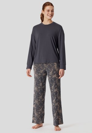 Grauer Langarmoberteil kombiniert mit leichten, gemusterten weiten Hosen mit floralen Designs in dunkelb blau und beige Tönen.