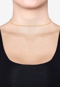 Gul choker halskæde med et delikat kædedesign, der har små led og en glat finish. Bæres ved halsbunden.