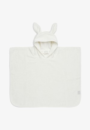 Poncho blanc à capuche en tissu éponge texturé, avec des oreilles de lapin sur la capuche, présentant une forme rectangulaire simple et un tissu doux.
