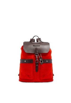 Zaino rosso texturizzato con due tasche frontali, patta in pelle marrone, cinturino con fibbia e manico superiore su sfondo bianco.