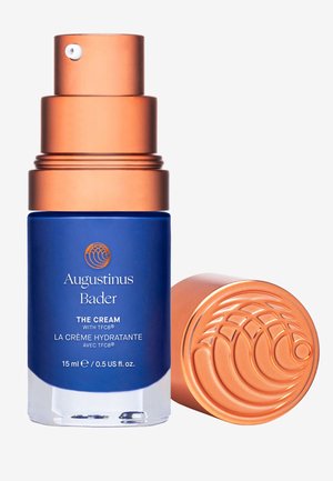 Blaue Glasflasche mit Pumpspender und Kupferdeckel. Mit erhabenem Design auf dem Deckel. Das Etikett trägt die Aufschrift "Die Creme mit TFC8." 15 ml.