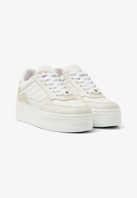 White platform sneakers made of suede and mesh, featuring laces, textured accents, and a rounded toe design with a thick sole.