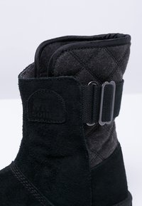 Schwarze Wildleder ankle boots mit grauem, gestepptem Textilobermaterial, runder Zehenform und verstellbarem Riemen mit Metallbeschlägen.