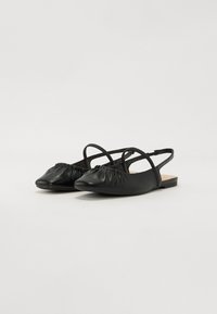 Ballerines à bride arrière en cuir noir avec un bout pointu, des détails froncés à l'avant et une semelle plate. Design minimaliste avec des fines lanières.