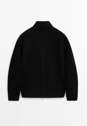 Schwarze Wildlederjacke mit geradem Schnitt, flachem Kragen und einem zentralen Reißverschluss am Saum, die eine glatte Textur und ein schlichtes Design zeigt.