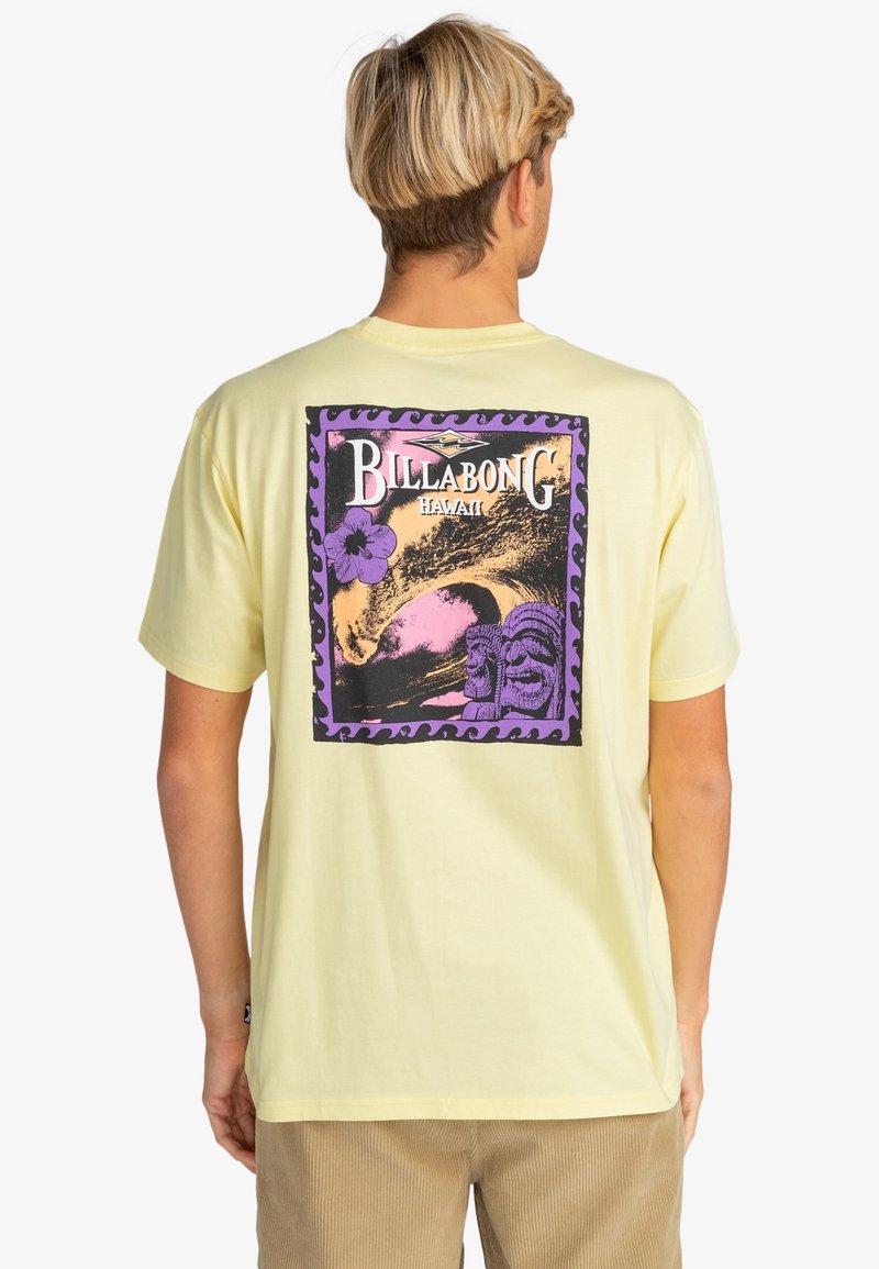 T-shirt en coton jaune présentant un grand graphisme violet et noir avec "Billabong Hawaii", une vague et des têtes tiki au dos.