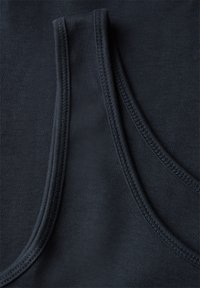 Primer plano de tela azul marino oscuro con dobladillos de doble costura visibles que crean bordes curvos y rectos sobre un material suave.