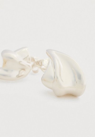 Ασημένια σκουλαρίκια με αφηρημένο σχήμα και γυαλιστερό φινίρισμα· λεία επιφάνεια και ρευστές καμπύλες δημιουργούν έναν διακριτικό σχεδιασμό.