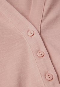 Cardigan rose clair en tissu doux et texturé, avec un décolleté en V et quatre boutons assortis le long de la patte de boutonnage.