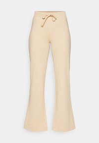 Beiga högmidjade stretchbyxor med elastisk midja och dragsko fram, utsvängda ben, visade mot en vit bakgrund.