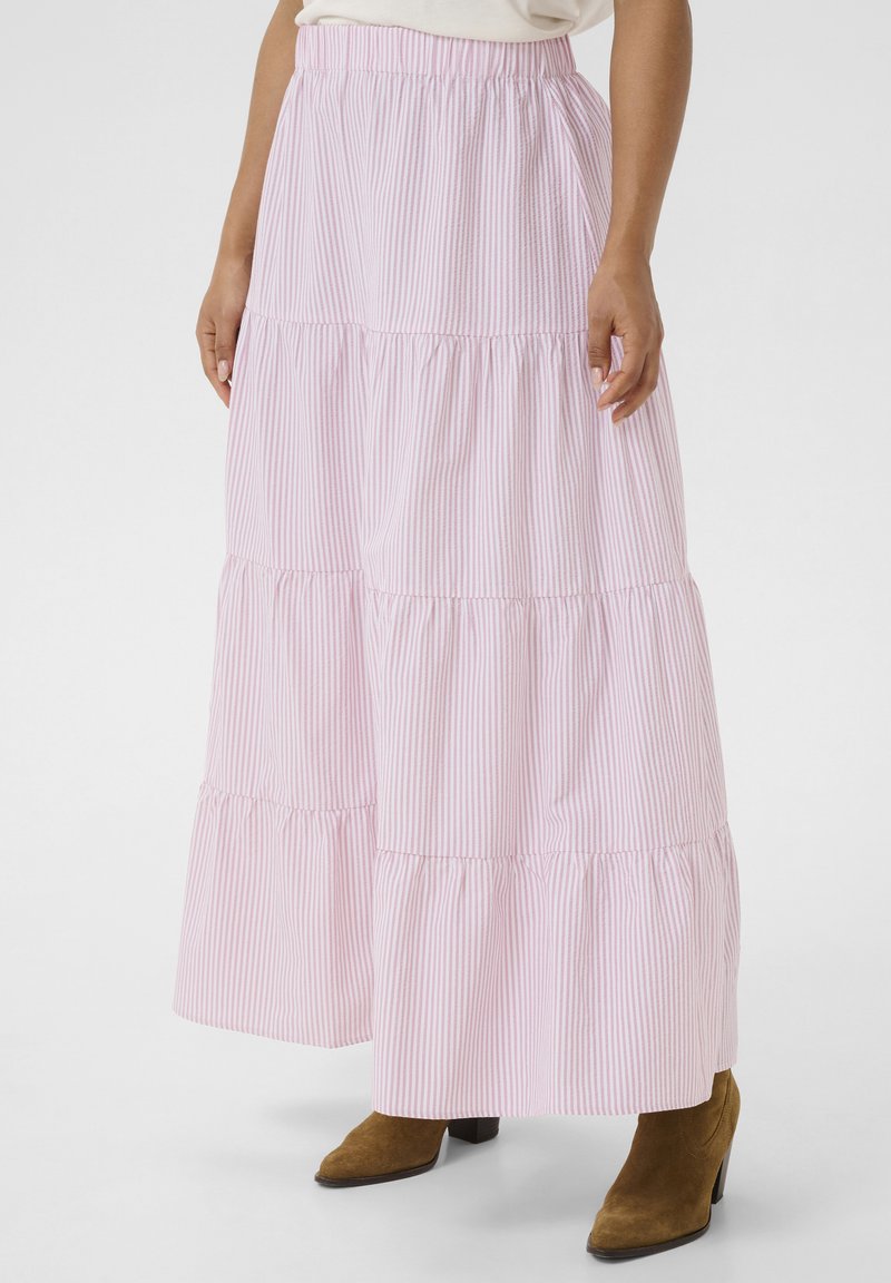 Jupe maxi à volants rayée rose et blanche avec une taille élastique, en tissu fluide et avec une coupe décontractée, associée à des bottines à talons marron.