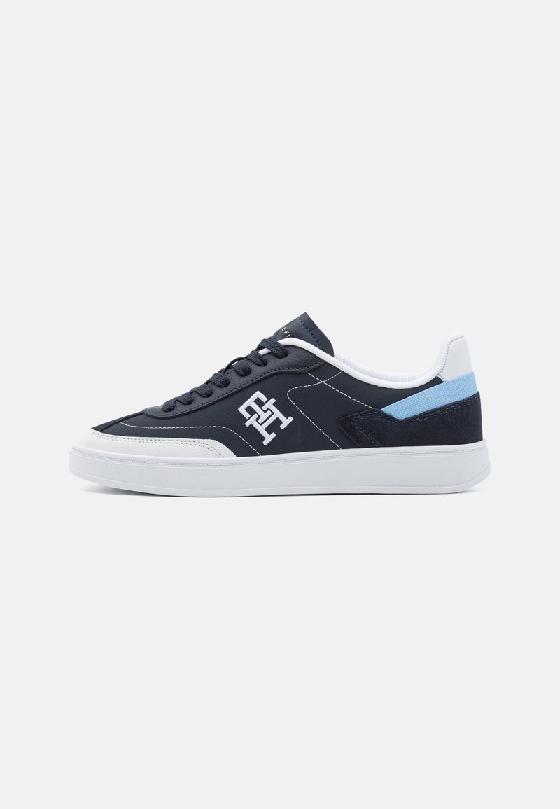 Baskets bleu marine avec semelles en caoutchouc blanc, présentant un panneau latéral texturé, des accents bleu clair et un logo sur le côté extérieur.