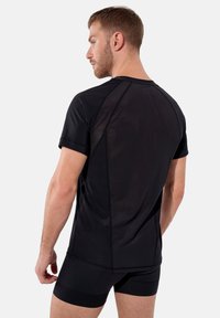 Svart atletisk tröja med korta ärmar, tillverkad av andningsbart meshtyg. Har en strömlinjeformad design och minimal sömdetalj.