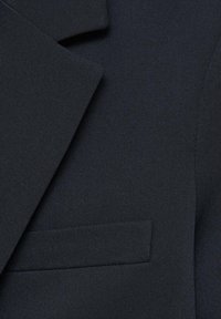 Tissu de blazer bleu marine à texture lisse, avec un revers pointu et une poche poitrine unique. Contour du blazer mis en avant.