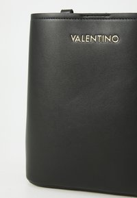 Zwarte leren handtas met een minimalistisch ontwerp. Voorzien van een gouden "Valentino" logo. Gladde textuur en rechthoekige vorm.