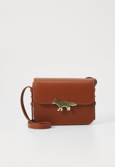 Le sac bandoulière en cuir marron présente un accent en métal doré en forme de renard, une forme rectangulaire, un rabat et une bandoulière ajustable.
