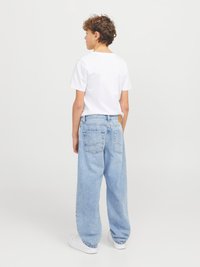 Hvit t-skjorte med klassisk passform, kombinert med lyseblå, ledige denimjeans med baklapp og store lommer. Hvite joggesko fullfører antrekket.