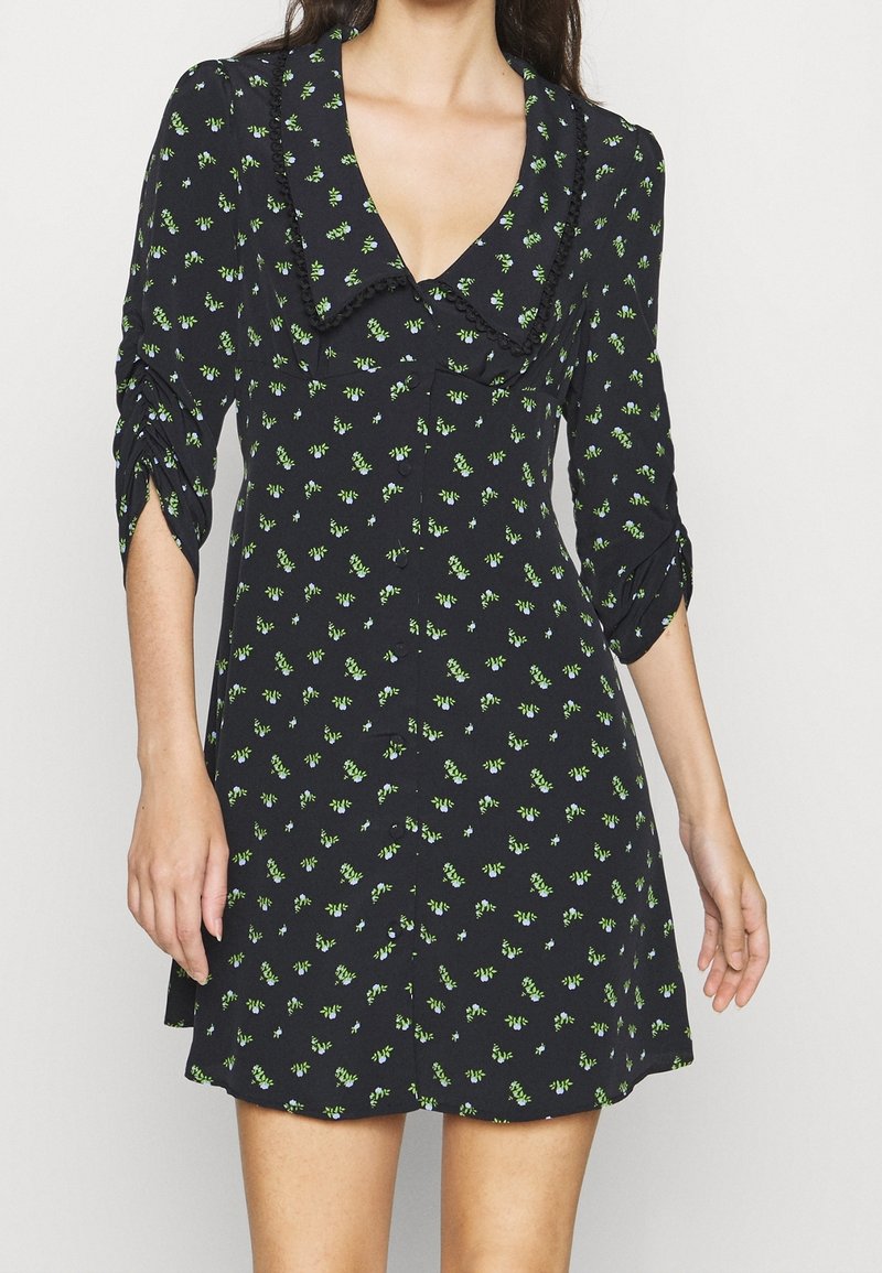 Schwarzes Kleid mit V-Ausschnitt, Dreiviertelärmeln und floralem Druck in Grün und Blau. Hergestellt aus weichem Stoff mit fließendem Design.