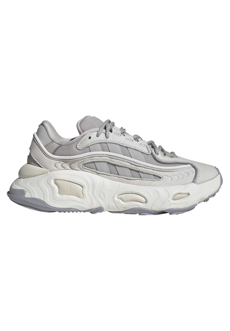 Grauer Sportschuh mit Obermaterial aus Mesh und Leder, gestaltet mit einer dicken, strukturierten Sohle, geschichteten Akzenten und Schnürverschluss.