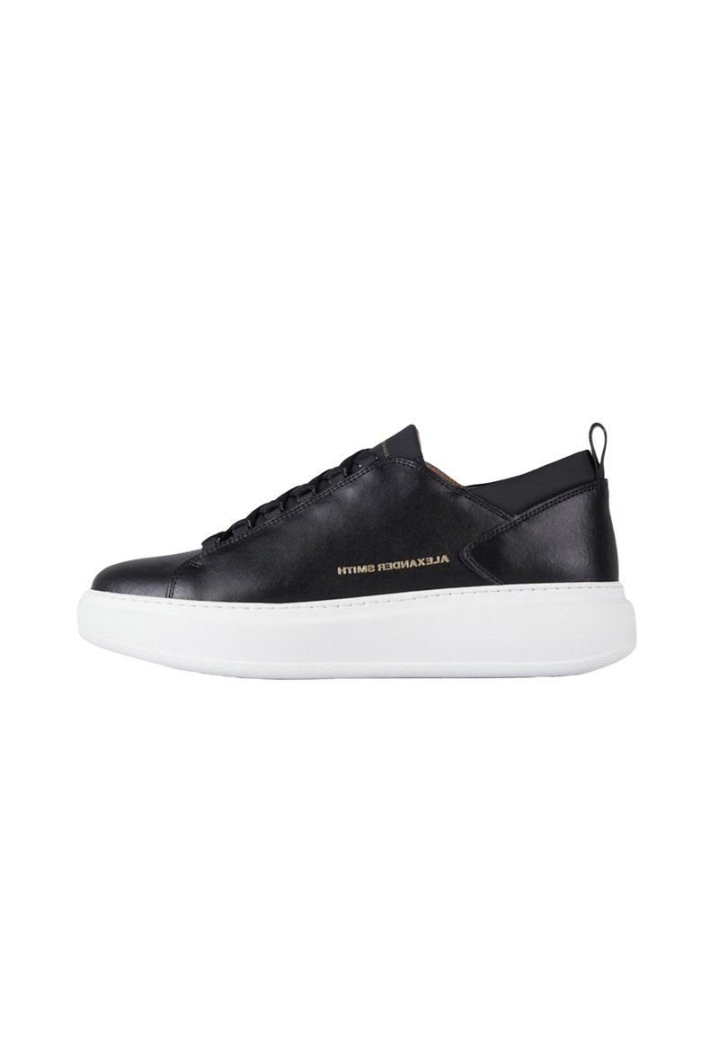 Sneaker nero low-top con suola bianca spessa, lacci neri, linguetta sul tallone e logo dorato "Alexander Smith" sul lato.