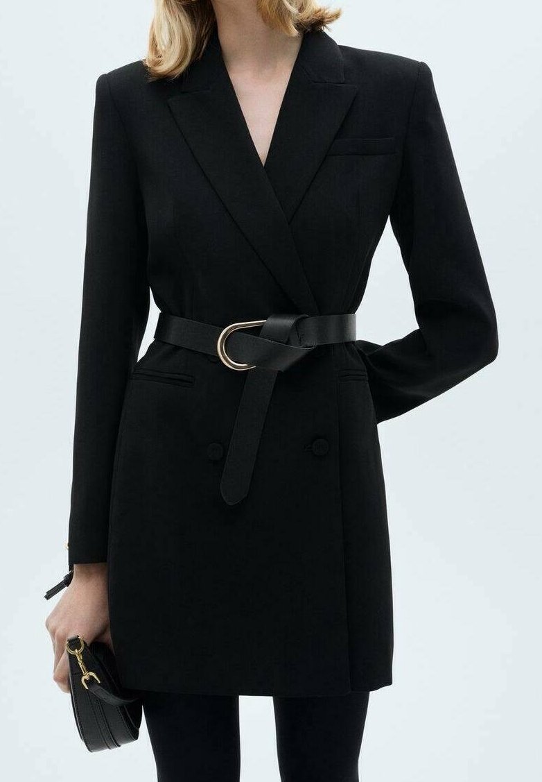 Abito giacca sartoriale nero con maniche lunghe, bottoni doppi, vita con cintura caratterizzata da una fibbia circolare dorata e due tasche laterali.